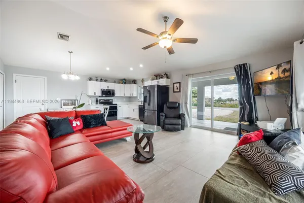 a living room with furniture kitchen view and a large window
