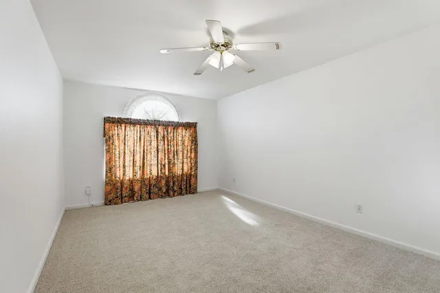 an empty room with a ceiling fan and window