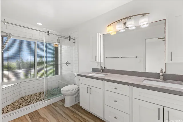 a bathroom with a granite countertop sink a toilet a mirror and shower