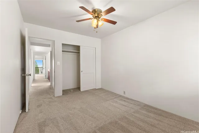 an empty room with closet and a chandelier fan