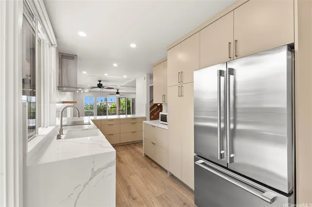 a kitchen with kitchen island a counter top space a refrigerator and white cabinets