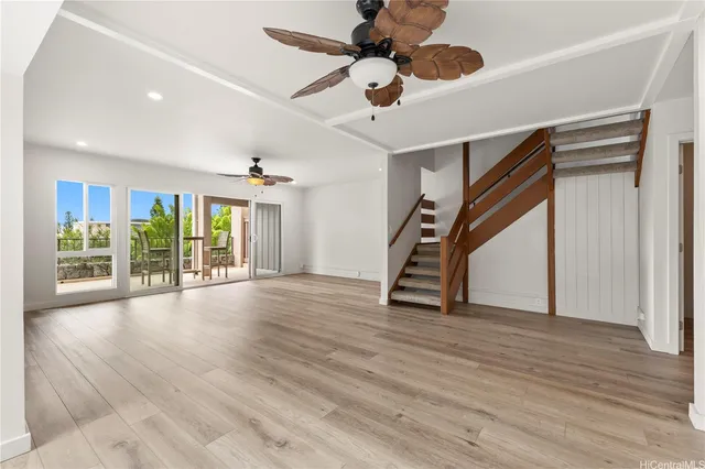 a view of an empty room with wooden floor and a ceiling fan