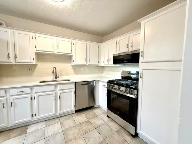 a kitchen with white cabinets and appliances