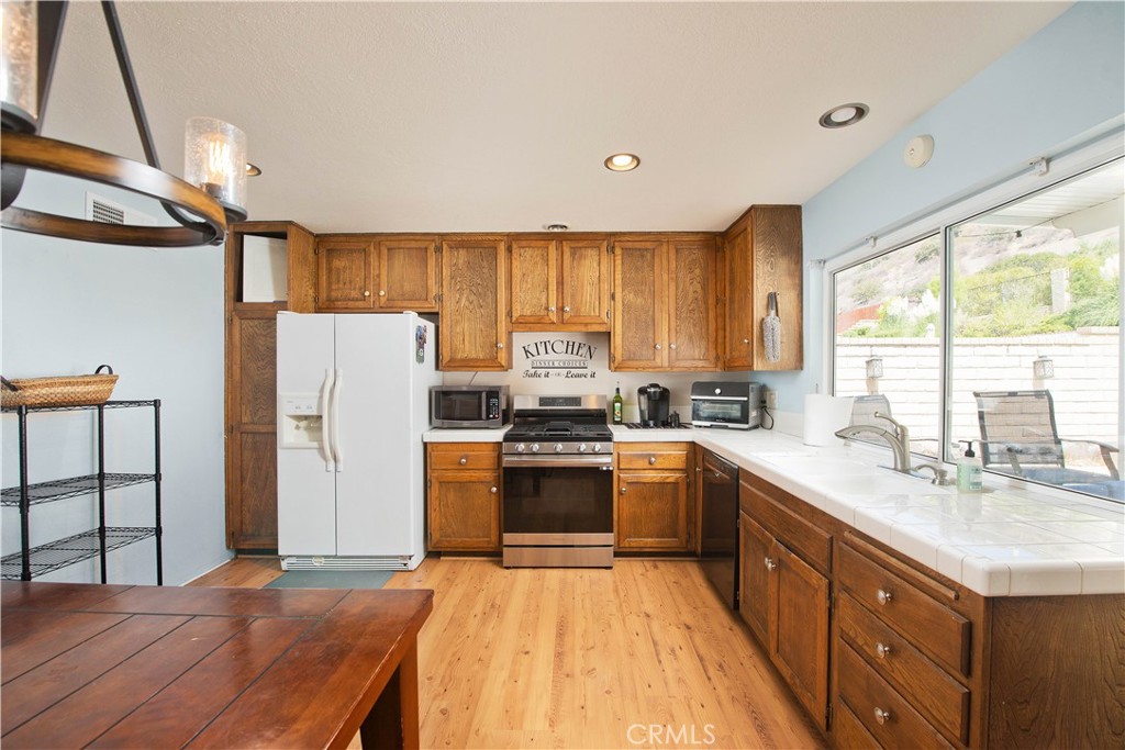 29262 Florabunda Road Canyon Country, CA 91387 - Photo 6 of 27 a kitchen with a refrigerator a sink dishwasher and wooden cabinets