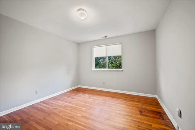 an empty room with wooden floor and window