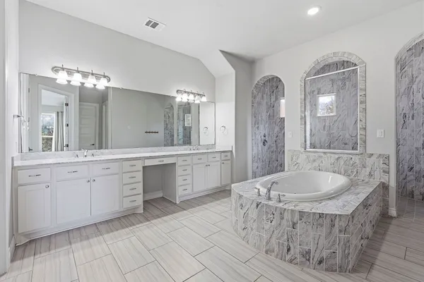 a spacious bathroom with a granite countertop sink a mirror and a bathtub