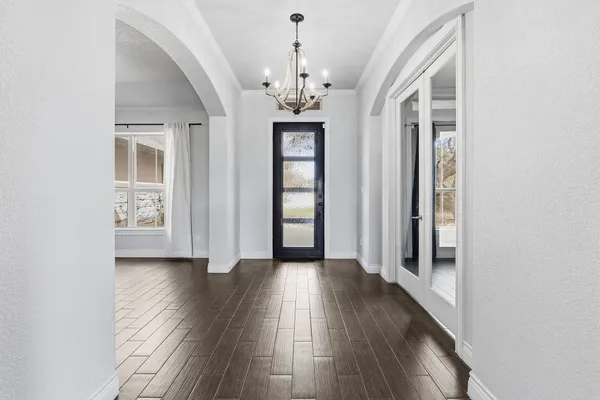 a view of a hallway with wooden floor and chandelier