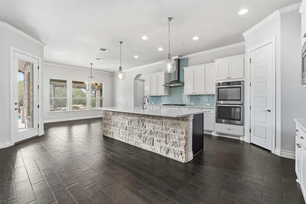 a large kitchen with stainless steel appliances granite countertop a large stove a sink dishwasher and a refrigerator with wooden floor