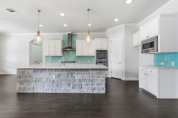 a large kitchen with stainless steel appliances granite countertop a large center island a stove a refrigerator a sink and a oven