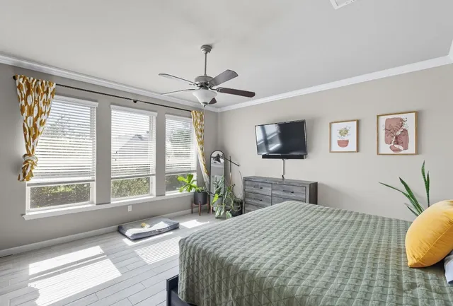 a bedroom with a bed a large window and wooden floor