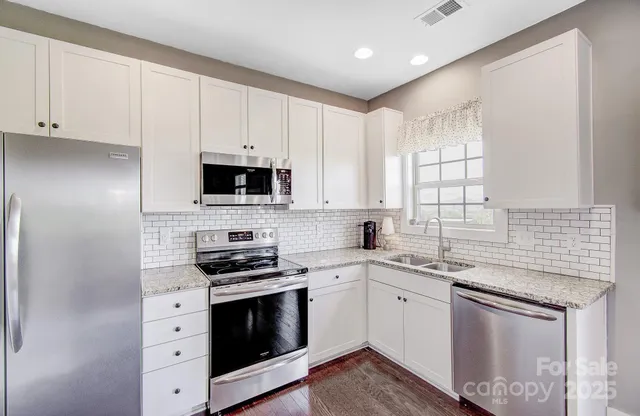 a kitchen with granite countertop white cabinets white stainless steel appliances and a sink