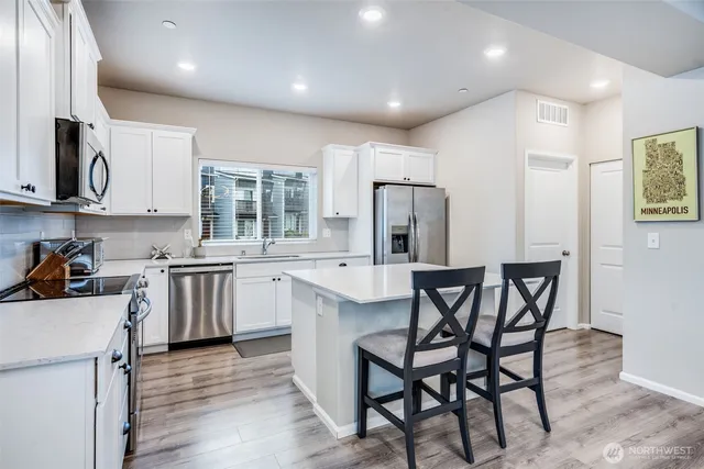 a kitchen with white cabinets and stainless steel appliances