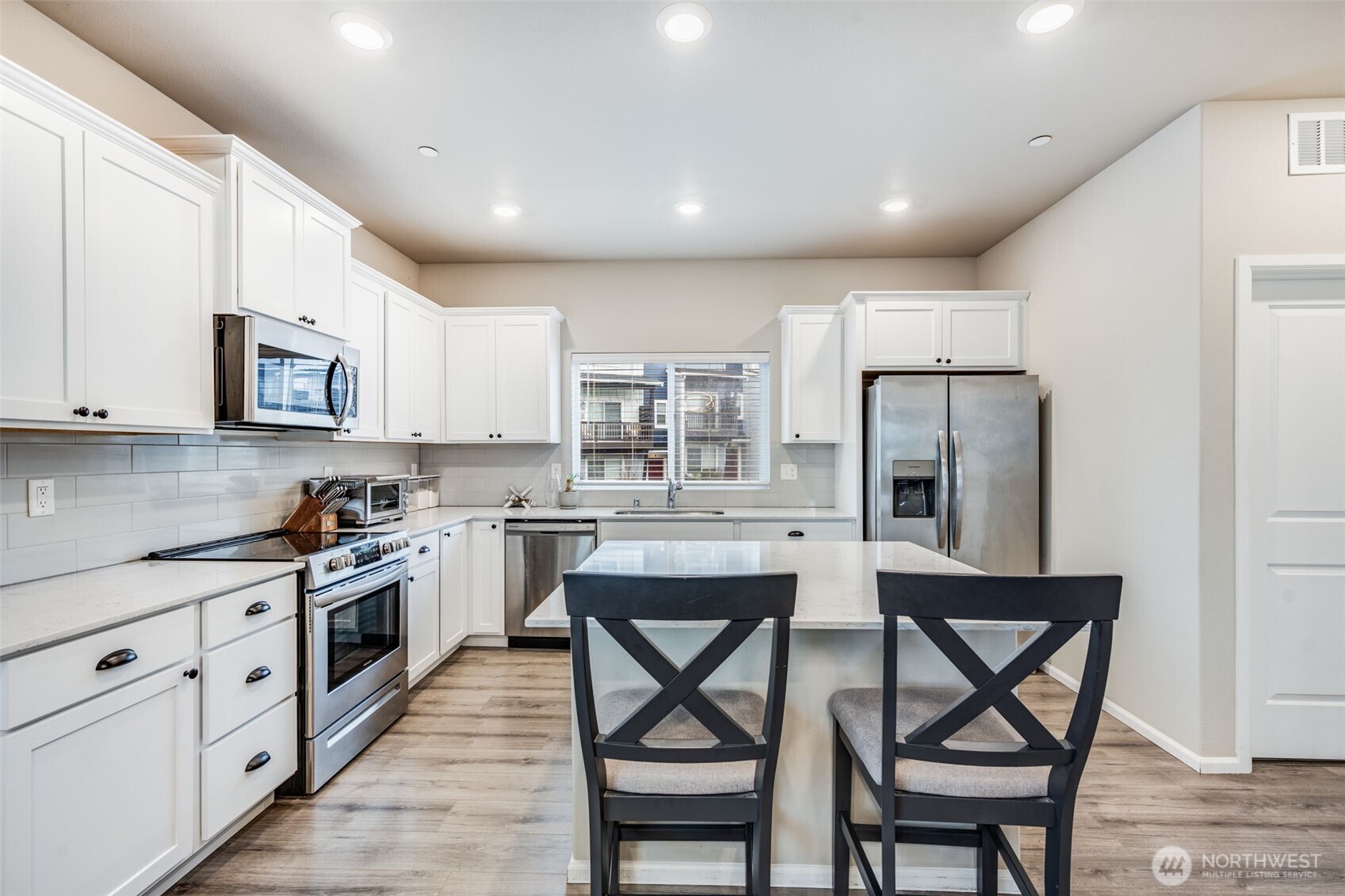 17539 110th Avenue East, Unit H Puyallup, WA 98374 - Photo 13 of 40 a kitchen with stainless steel appliances kitchen island a table chairs refrigerator and microwave