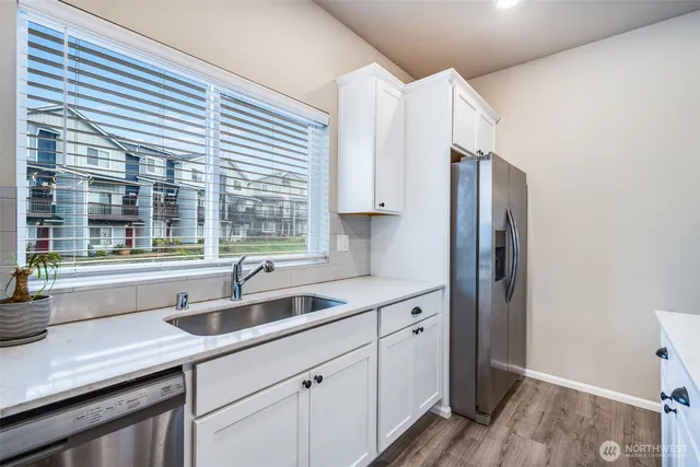 a kitchen with stainless steel appliances a sink a refrigerator and a window