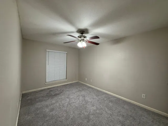 a view of an empty room with a chandelier fan