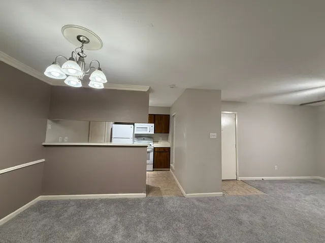 an empty room with a chandelier fan and windows