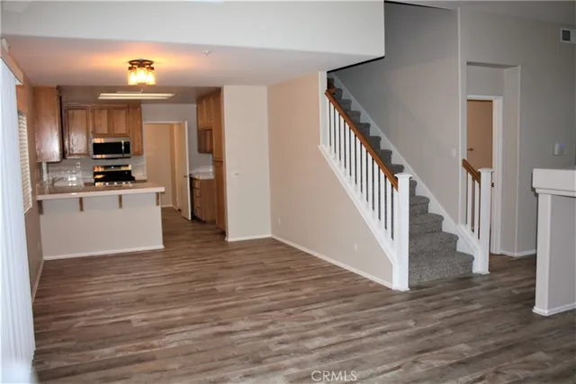 a view of a kitchen with wooden floor electronic appliances and stairs