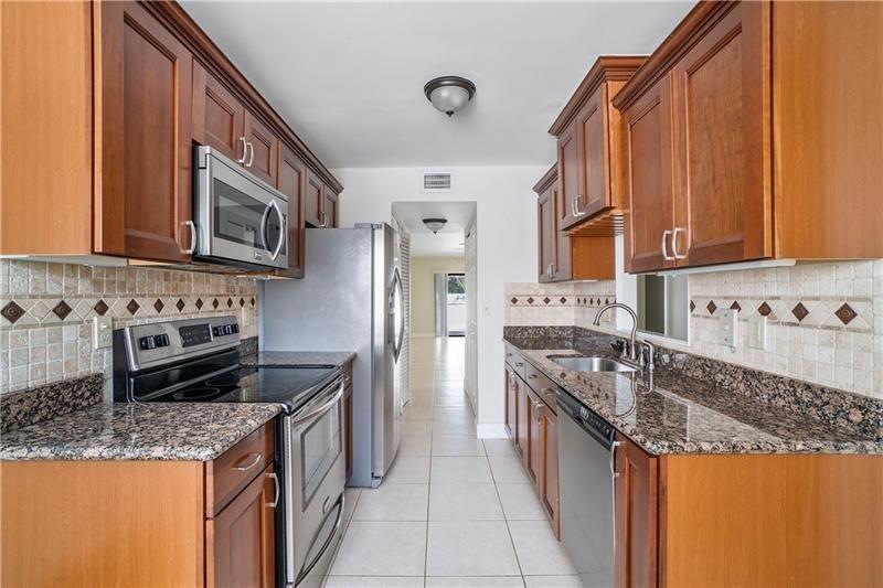 9769 Riverside Drive, Unit 712 Coral Springs, FL 33071 - Photo 5 of 18 a kitchen with stainless steel appliances granite countertop a stove and a sink