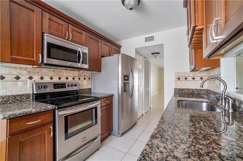 9769 Riverside Drive, Unit 712 Coral Springs, FL 33071 - Photo 6 of 18 a kitchen with stainless steel appliances granite countertop a stove microwave and refrigerator