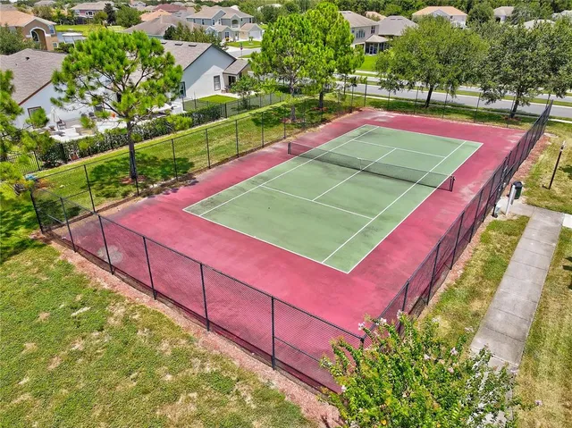 a view of a tennis ground with large trees