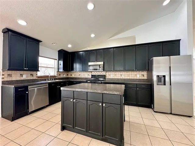 a kitchen with granite countertop a refrigerator and a stove top oven