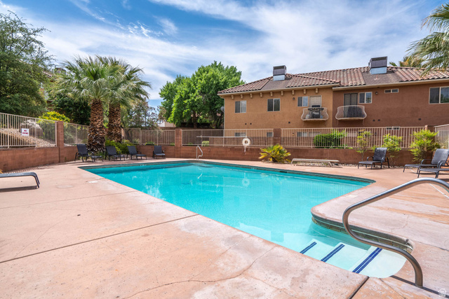 700 North Main Street, Unit F3 Washington, UT 84780 - Photo 31 of 34 Outdoor swimming pool with concrete decking and integrated entry steps, surrounded by mature palm trees and a perimeter fence