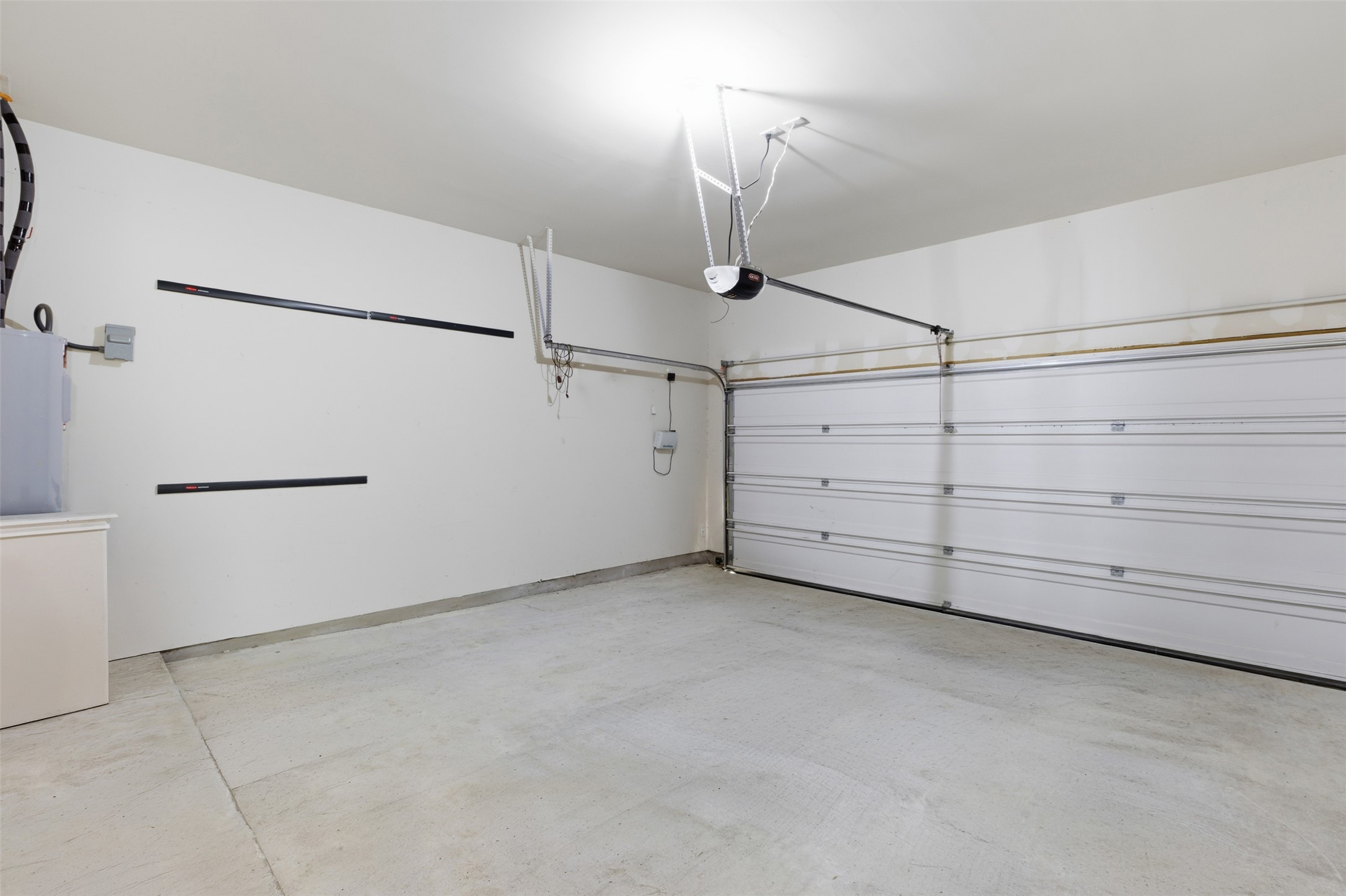 124 Golden Eagle Leander, TX 78641 - Photo 28 of 32 The garage with automated door opener has an extended area. The far wall has the sprinkler controls.