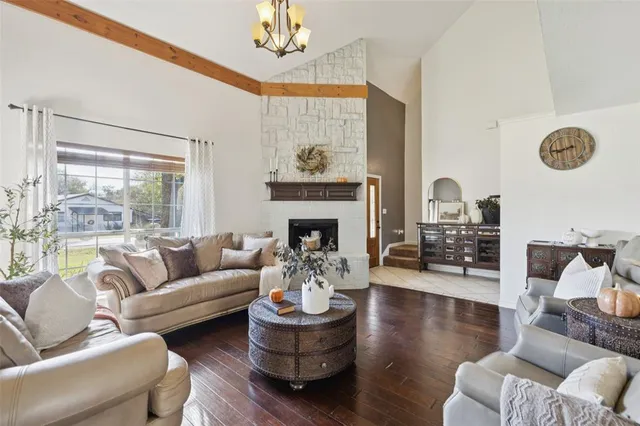 a living room with couches a fireplace and a dining table with wooden floor