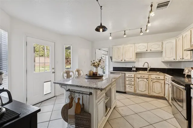 a kitchen with stainless steel appliances kitchen island a table chairs in it and white cabinets
