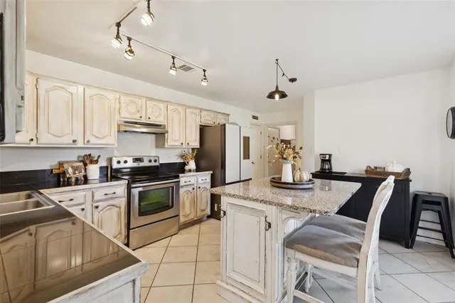 a kitchen with granite countertop white cabinets and stainless steel appliances