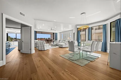 a view of a dining room with furniture a kitchen and chandelier