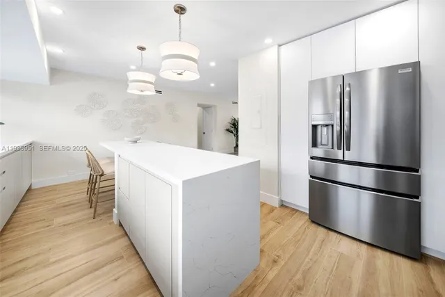 a kitchen with a refrigerator a sink and wooden floor