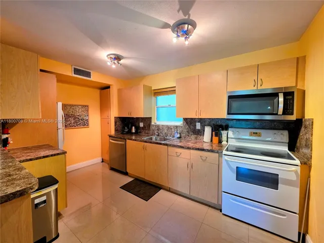 a kitchen with granite countertop cabinets stainless steel appliances and a counter space