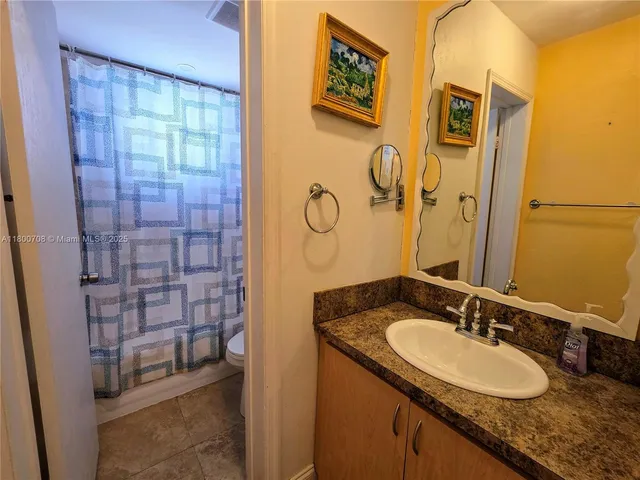 a bathroom with a granite countertop sink a mirror a vanity and shower
