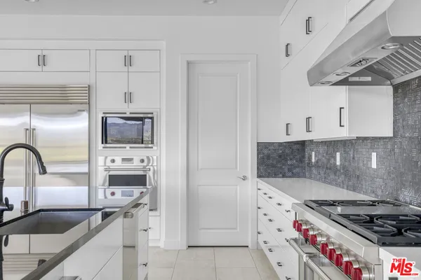 a kitchen with granite countertop a stove a sink and a refrigerator