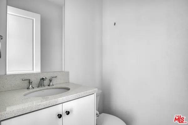 a bathroom with a granite countertop sink and a toilet