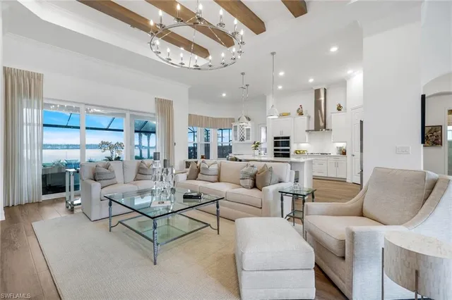 a living room with furniture kitchen view and a chandelier