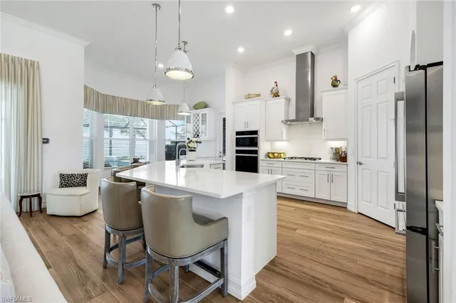 a kitchen with kitchen island stainless steel appliances a dining table chairs sink and wooden floor