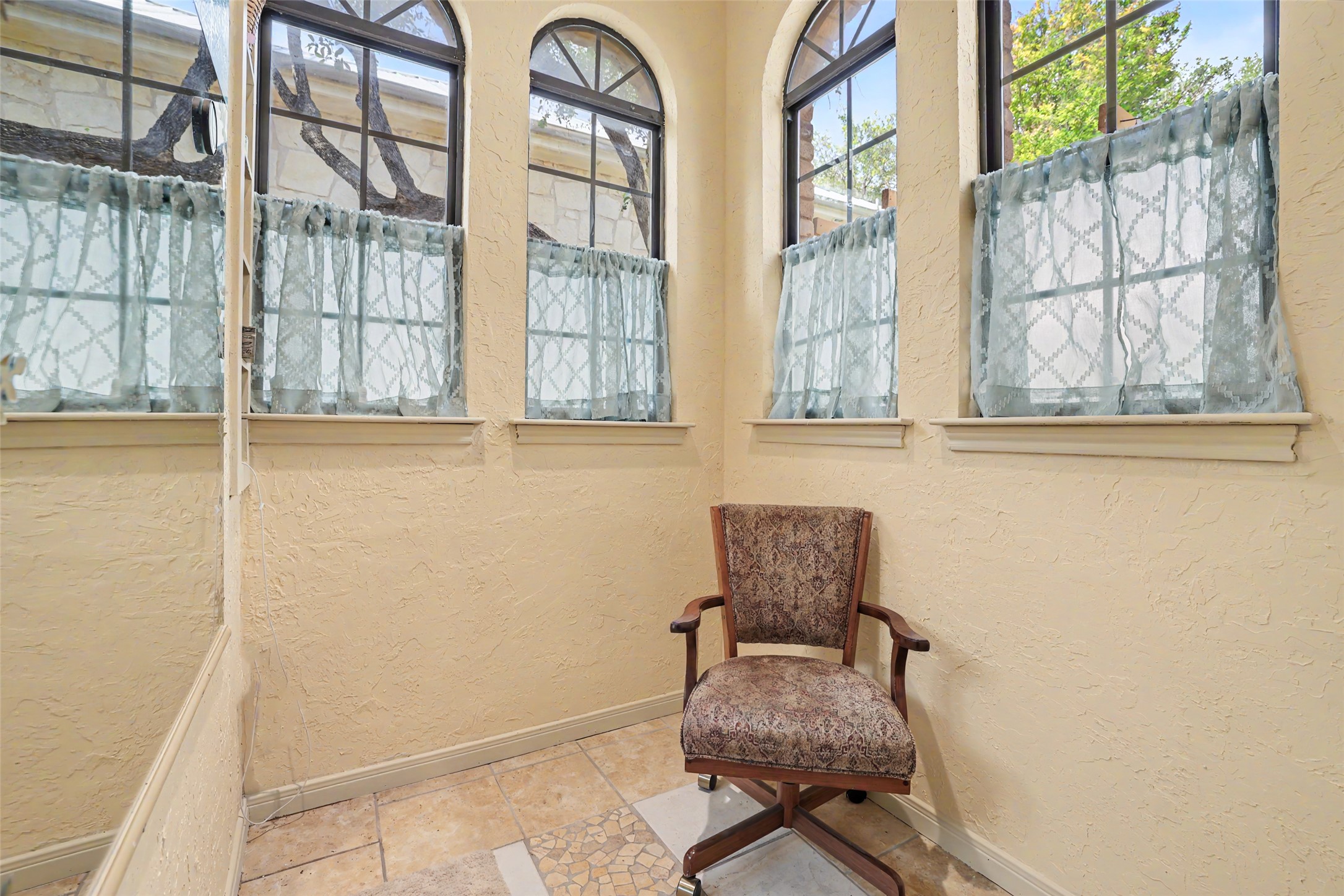 110 South Ridge Circle Georgetown, TX 78628 - Photo 19 of 37 Corner dressing and vanity nook featuring arched windows with black frames, textured beige walls, and tile flooring