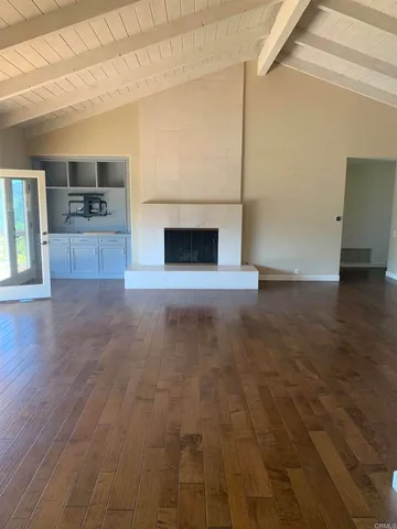 a view of empty room with kitchen and fireplace
