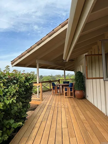 a view of roof deck with table and chairs under an umbrella with wooden floor