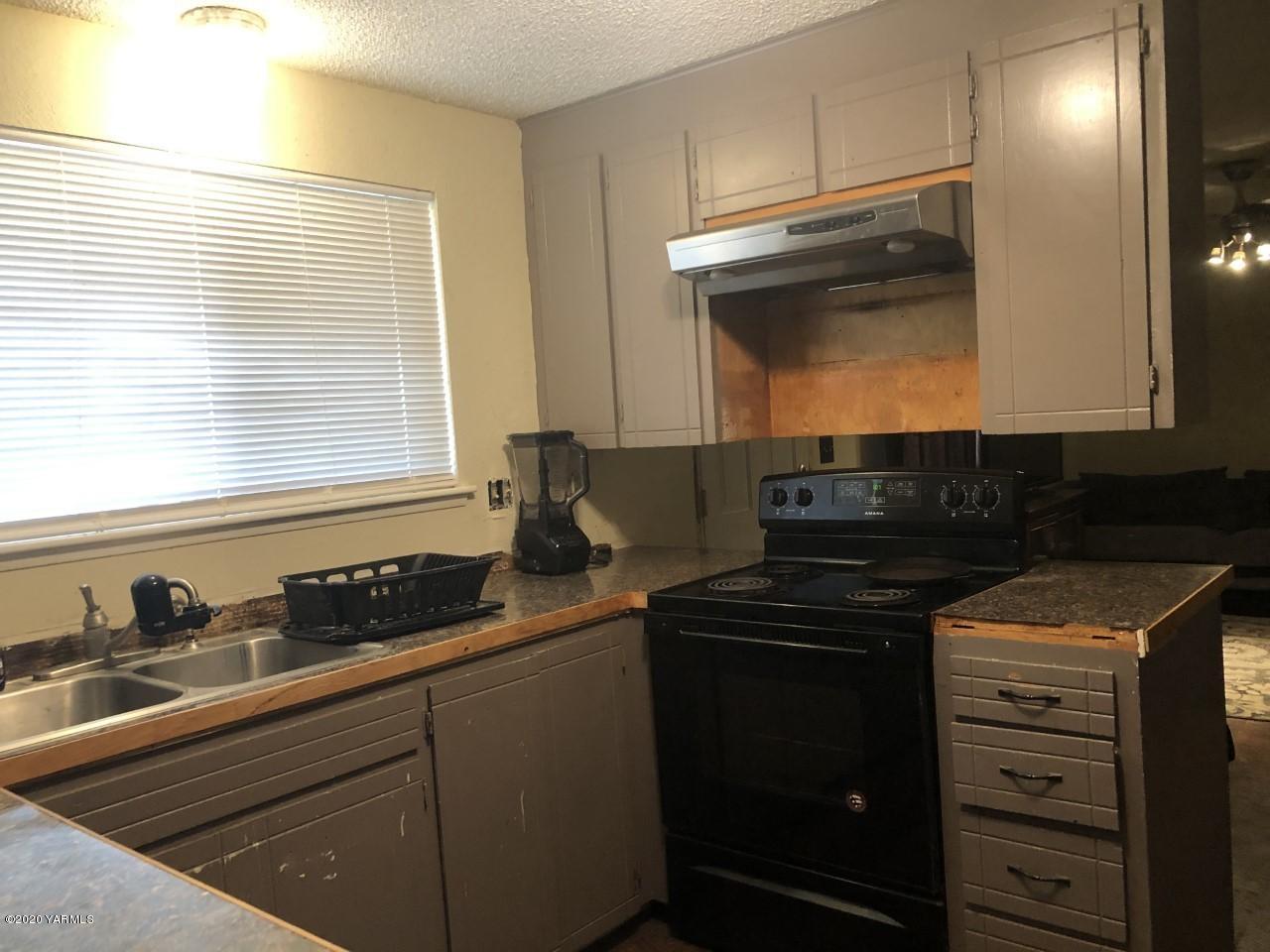 796 East Allen Road Sunnyside, WA 98944 - Photo 7 of 15 a kitchen with granite countertop white cabinets and black appliances