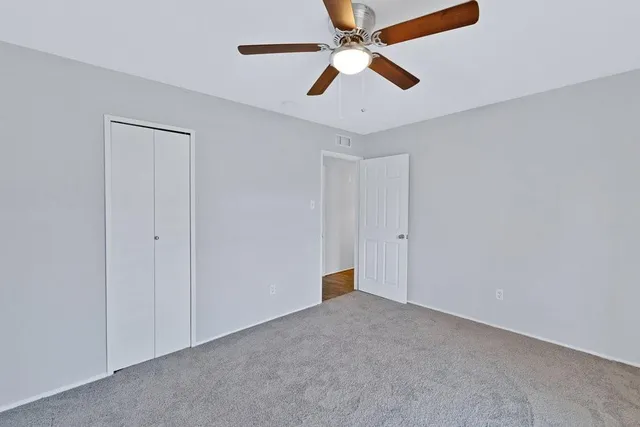 an empty room with closet and a ceiling fan