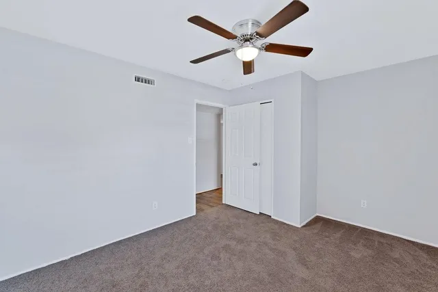 an empty room with a ceiling fan and a fan