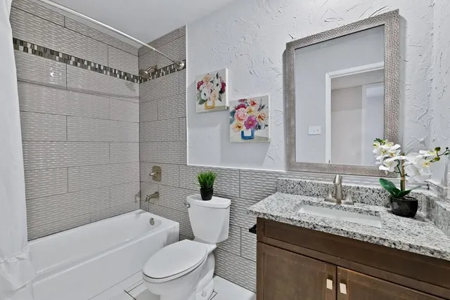 a bathroom with a granite countertop sink a toilet and bathtub