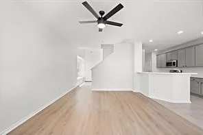 a view of empty room with wooden floor and ceiling fan