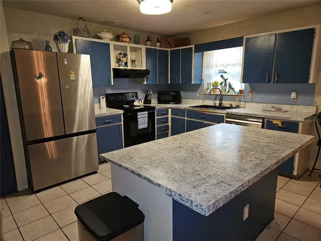 a kitchen with stainless steel appliances granite countertop a refrigerator and a stove top oven