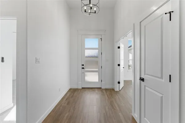 a view of a hallway with wooden floor and a bathroom