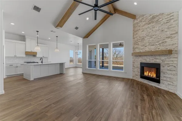 an empty room with wooden floor a fireplace and windows