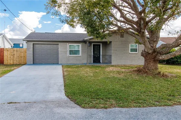 a view of a house with a large tree and a yard